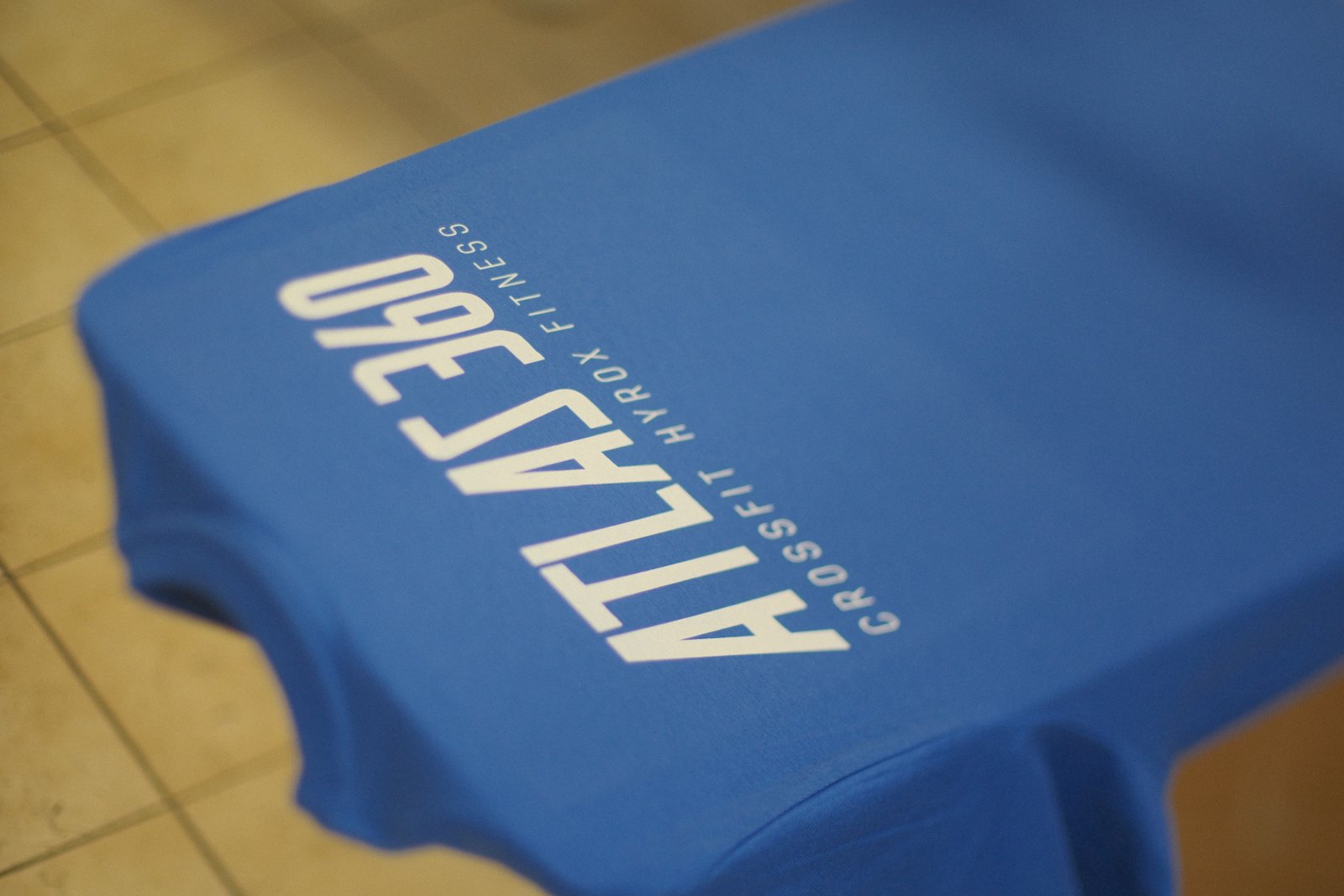 Blaues Atlas-360-Crossfit-Hyrox-Shirt mit weißem Schriftzug im klassischen Siebdruck — frühere Edition