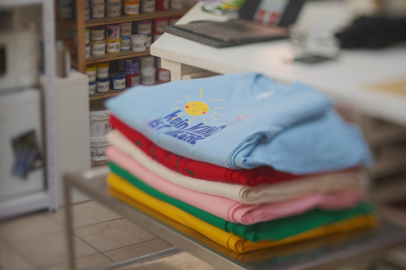 Kampagnen-Shirts der Kinderfreunde Steiermark in vielen Farben — Siebdruck mit Slogans 'Kein Kind ist illegal' und 'The kids are alright'