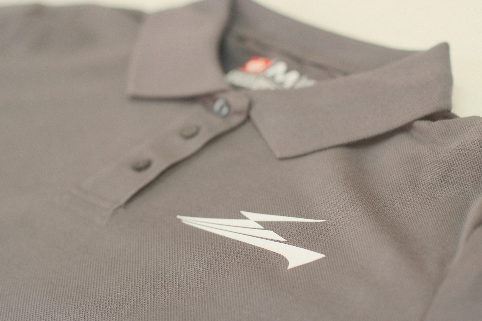 Graues Arbeitspoloshirt mit weißem, erhabenem 3D-Silikon-Logo auf der Brust