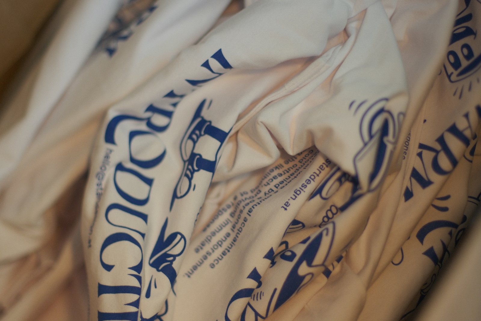Aufgefalteter Stapel der fertig bedruckten Start-Design-Shirts — Oversized Boxy Tee mit großem Backprint in Pantone 293 U