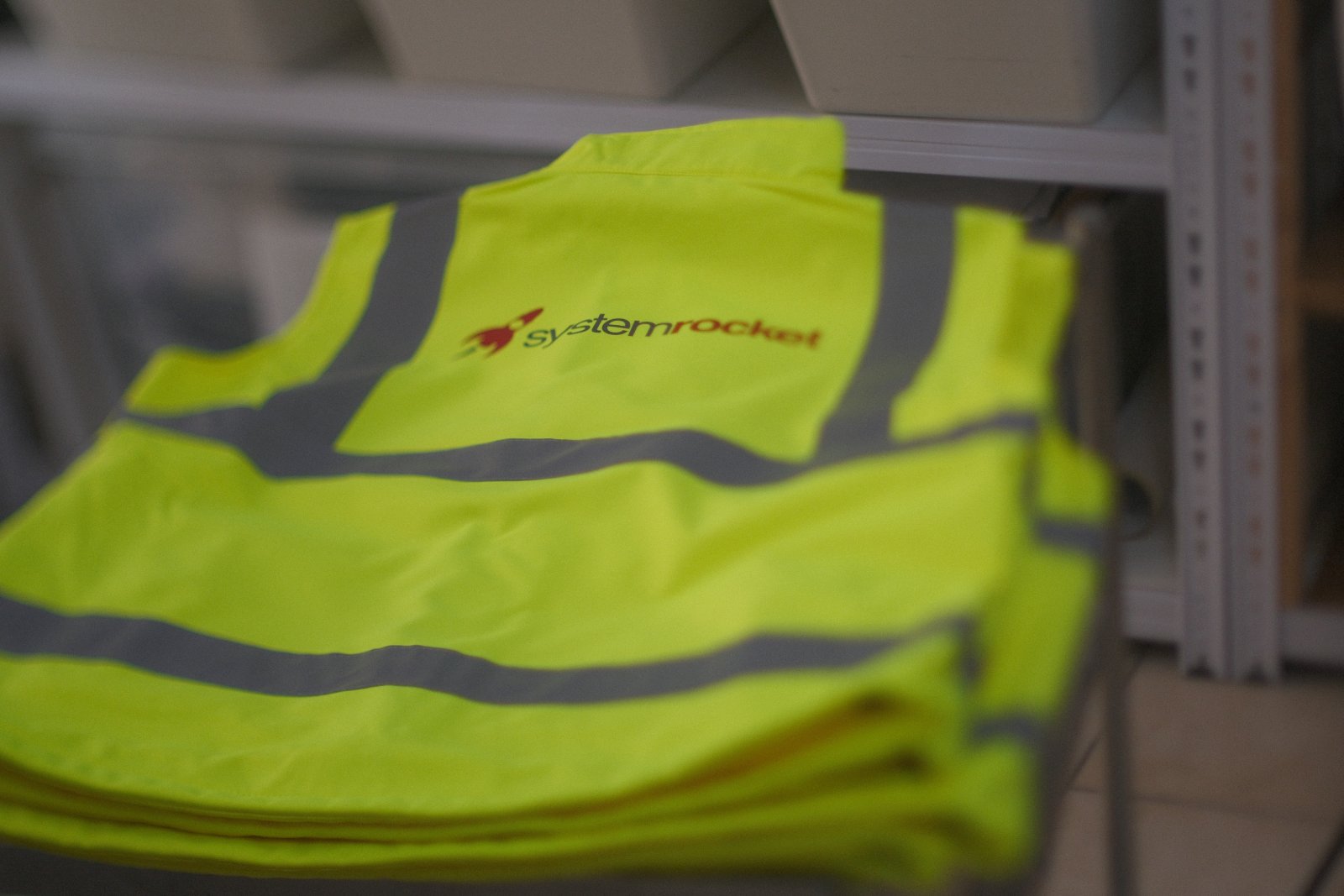 Stapel bedruckter Warnwesten mit Firmenlogo, bereit zur Auslieferung