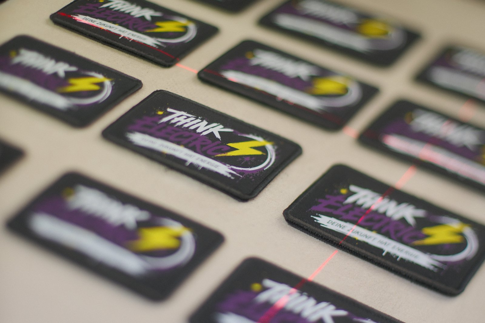 Reihe der bedruckten Think-Electric-Klett-Patches in mehreren Motiv-Varianten — austauschbar an den Trucker-Caps